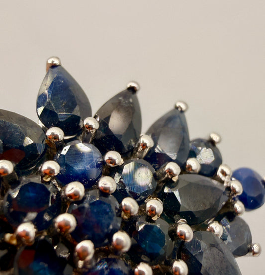 Close-up of faceted blue sapphires in sterling silver floral pendant