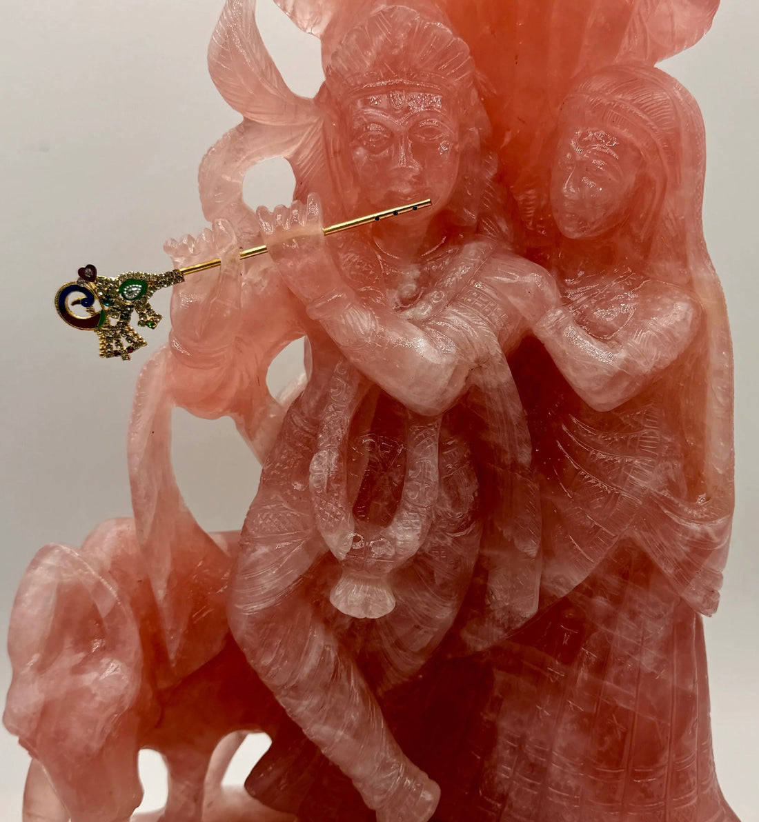 Hand-carved rose quartz Krishna and Radha crystal statue featuring Krishna playing a golden flute.