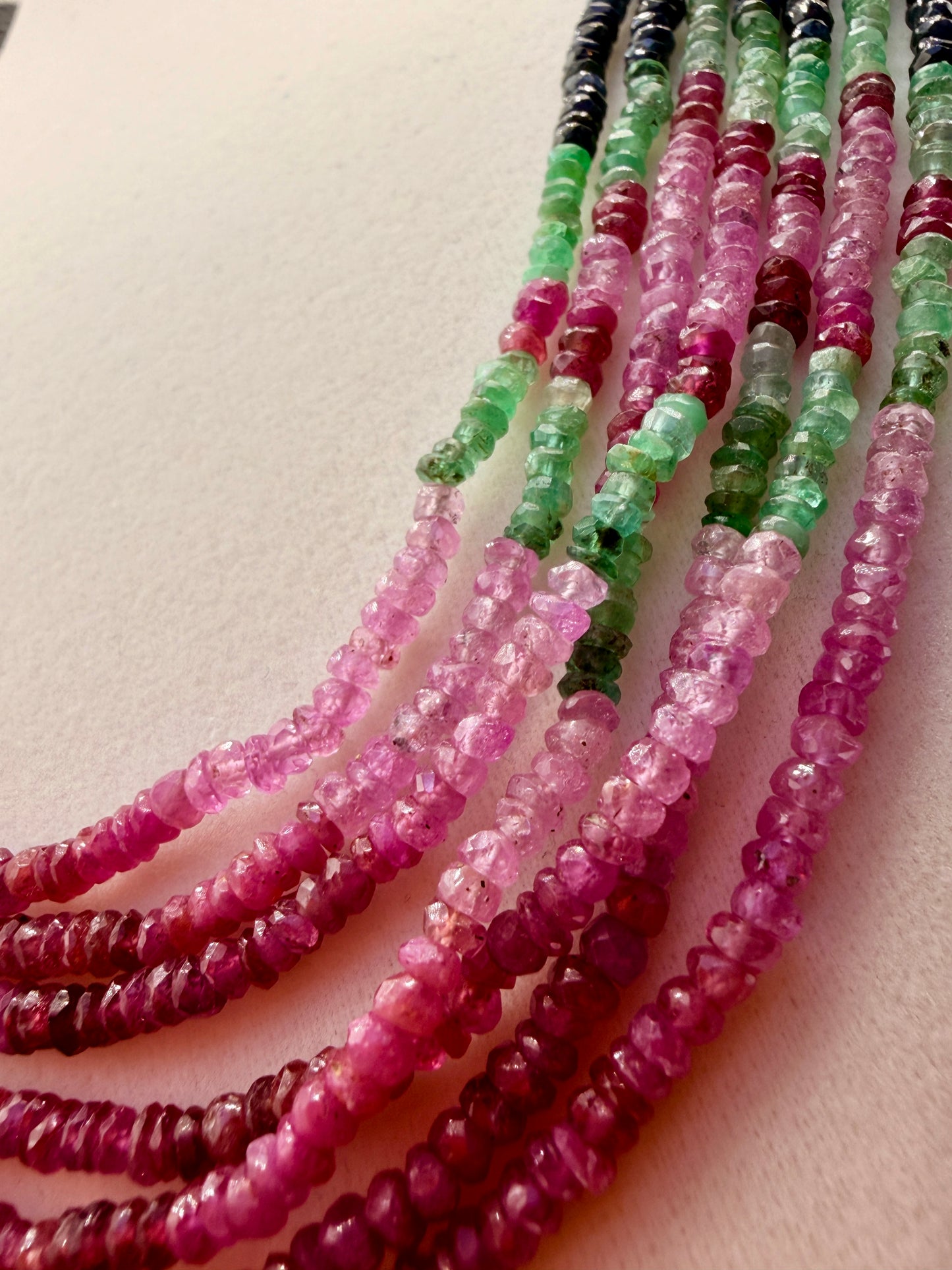 Close-up of natural pink sapphire and green emerald faceted beads