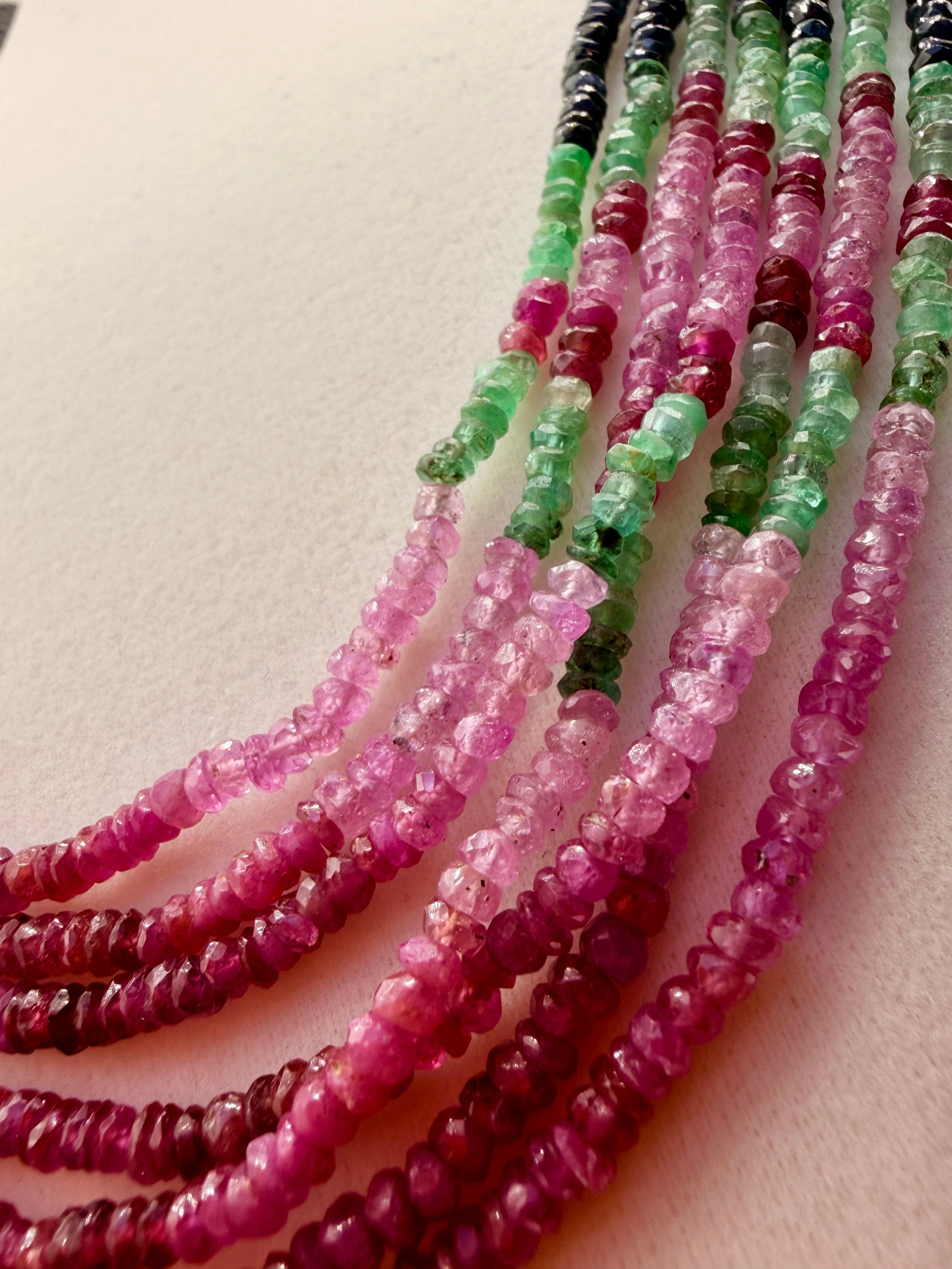Close-up of natural pink sapphire and green emerald faceted beads