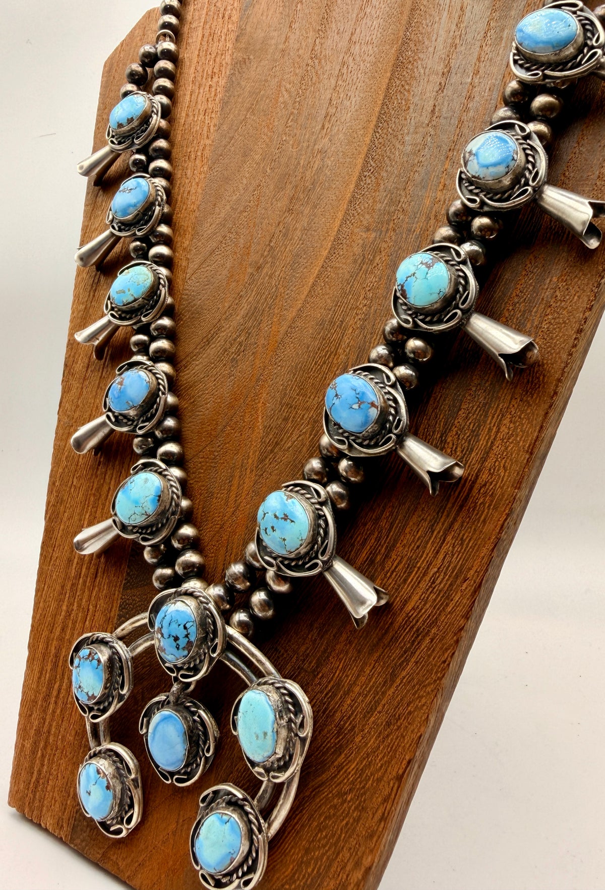 Angled view of 28-inch Golden Hills turquoise squash blossom necklace